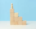Wooden figurine of a man on top of wooden cubes. The concept of purposefulness, achieving goals, overcoming obstacles