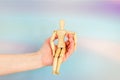 wooden figurine of man in woman's hand. little man sits in woman's palm. concept of care, insurance