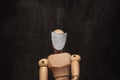 A wooden figurine, a mannequin sits in a white empty mask as a concept of the crisis of self-indiification.