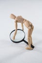 Wooden figurine picking up a magnifying glass