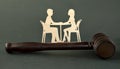 Wooden figurines of a man and a woman sitting at a table against the background of a judge`s hammer