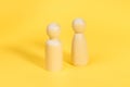 Wooden figurines of man and woman on yellow backdrop, relationship, communication problems.