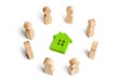 Wooden figurines of people stand around a green house. Search for a new home and real estate. Buying or selling a home.