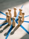 Wooden figurines representing a network of human connections on a light wooden surface with blue lines Royalty Free Stock Photo