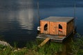 Fisherman house boat anchored at grassy bank of river dam with simple wooden plank bridge as molo pier