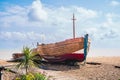 Wooden fishing boat moored on a pebble beach. The mast is in the shape of a cross Royalty Free Stock Photo