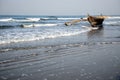 Wooden fishing boat near the shore against the background of blue sea and morning sky. Old boat with oars in waves, coast of the Royalty Free Stock Photo