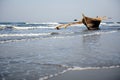 Wooden fishing boat near the shore against the background of blue sea and morning sky. Old boat with oars in waves, coast of the Royalty Free Stock Photo