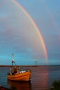 Wooden fishing boat and rainbow in the sky