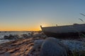 wooden fishing boat on the seashore against the sky illuminated by the setting sun