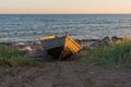 wooden fishing boat on the seashore against the sky illuminated by the setting sun