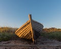 wooden fishing boat on the seashore against the sky illuminated by the setting sun