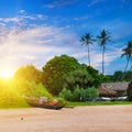 Wooden fishing boats on the sandy beach. Tropical landscape with palm trees and bright sunset Royalty Free Stock Photo
