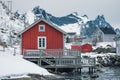 Wooden fishing cottage rorbuer on coastline surrounded by snowy mountain on winter at Nordland, Lofoten Islands