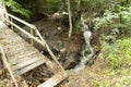 Wooden flooring of a dilapidated bridge with a railing for safety across a mountain river on an ecological trail in a summer Royalty Free Stock Photo