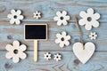 Wooden flowers, heart, black chalk board on a blue grey knotted old wooden background with empty space layout Royalty Free Stock Photo