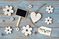 Wooden flowers, heart, black chalk board and with love label on a blue grey knotted old wooden background with empty space layout Royalty Free Stock Photo