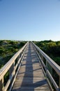 Wooden foot path over the sand dunes at the beach on a sunny day. Royalty Free Stock Photo