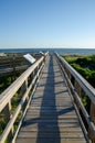 Wooden foot path over the sand dunes at the beach on a sunny day. Royalty Free Stock Photo