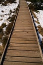 A wooden footbridge in the high moor with snow in spring Royalty Free Stock Photo