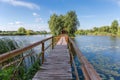 Wooden footbridge to island with hut and trees on lake Royalty Free Stock Photo