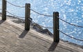 Wooden footpath along the coast with a fence with a rope. Sea summer landscape Royalty Free Stock Photo