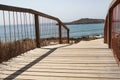 Wooden footpath on a beach entrance near Porto Covo, Portugal. Peach tree island in the background. Royalty Free Stock Photo