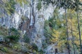 Wooden footpath and waterfall on a rocky mountain in a forest on an autumn day.