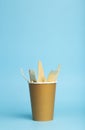 Wooden forks, knives and spoons for food in a paper cup on a colored background. Eco-friendly disposable tableware without plastic Royalty Free Stock Photo