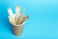 Wooden forks, knives and spoons for food in a paper cup on a colored background. Eco-friendly disposable tableware without plastic Royalty Free Stock Photo