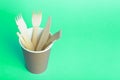 Wooden forks, knives and spoons for food in a paper cup on a colored background. Eco-friendly disposable tableware without plastic Royalty Free Stock Photo