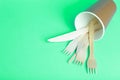 Wooden forks, knives and spoons for food in a paper cup on a colored background. Eco-friendly disposable tableware without plastic Royalty Free Stock Photo