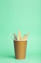 Wooden forks, knives and spoons for food in a paper cup on a colored background. Eco-friendly disposable tableware without plastic Royalty Free Stock Photo