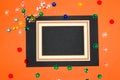 wooden frame on black orange background, frame as copy space, around colorful fake gemstone