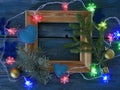 Wooden frame decorated with fir branches, Christmas-tree lighting with snowflakes, felt hearts on a blue wooden textural backgroun Royalty Free Stock Photo