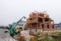 Wooden frame of a house under construction with a crane lifting supplies