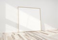 Wooden frame leaning in bright white interior with wooden floor mockup 3D rendering