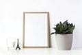 Wooden frame mockup on white table with potted plant