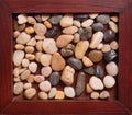 A wooden frame with sea pebbles, very close-up. Royalty Free Stock Photo