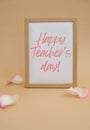 Wooden frame with text HAPPY TEACHERS DAY on paper blank and delicate pink rose petals on beige background. Romantic