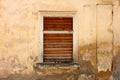Wooden frame window with closed wooden blinds on abandoned stone house with dilapidated facade Royalty Free Stock Photo