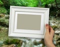 Wooden frame in woman hands. background of the Natural Spring Waterfall Royalty Free Stock Photo