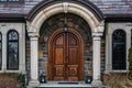 A wooden front door framed by a stone archway in a large home building Royalty Free Stock Photo