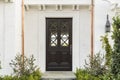 Wooden front door of white brick home with plants