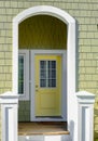 Wooden front yellow door of a home. Front view of a door on a house with the porch and front walkway Royalty Free Stock Photo