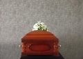 Wooden funeral casket with white lilies at grey