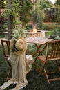 Wooden furniture in the garden against the backdrop of a fire on the patio. Among the branches of the bush stands a wooden table Royalty Free Stock Photo