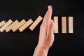 Wooden game strategy, hand stopping falling wooden dominoes effect of continuous overthrown or risk, strategy and successful inter Royalty Free Stock Photo