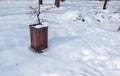 Wooden garbage or junk can for trash in the park covered with snow in the winter season to protect from environment pollution Royalty Free Stock Photo