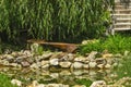 Wooden garden bench in the shape of half a circle by a rocky pond surrounded by greenery